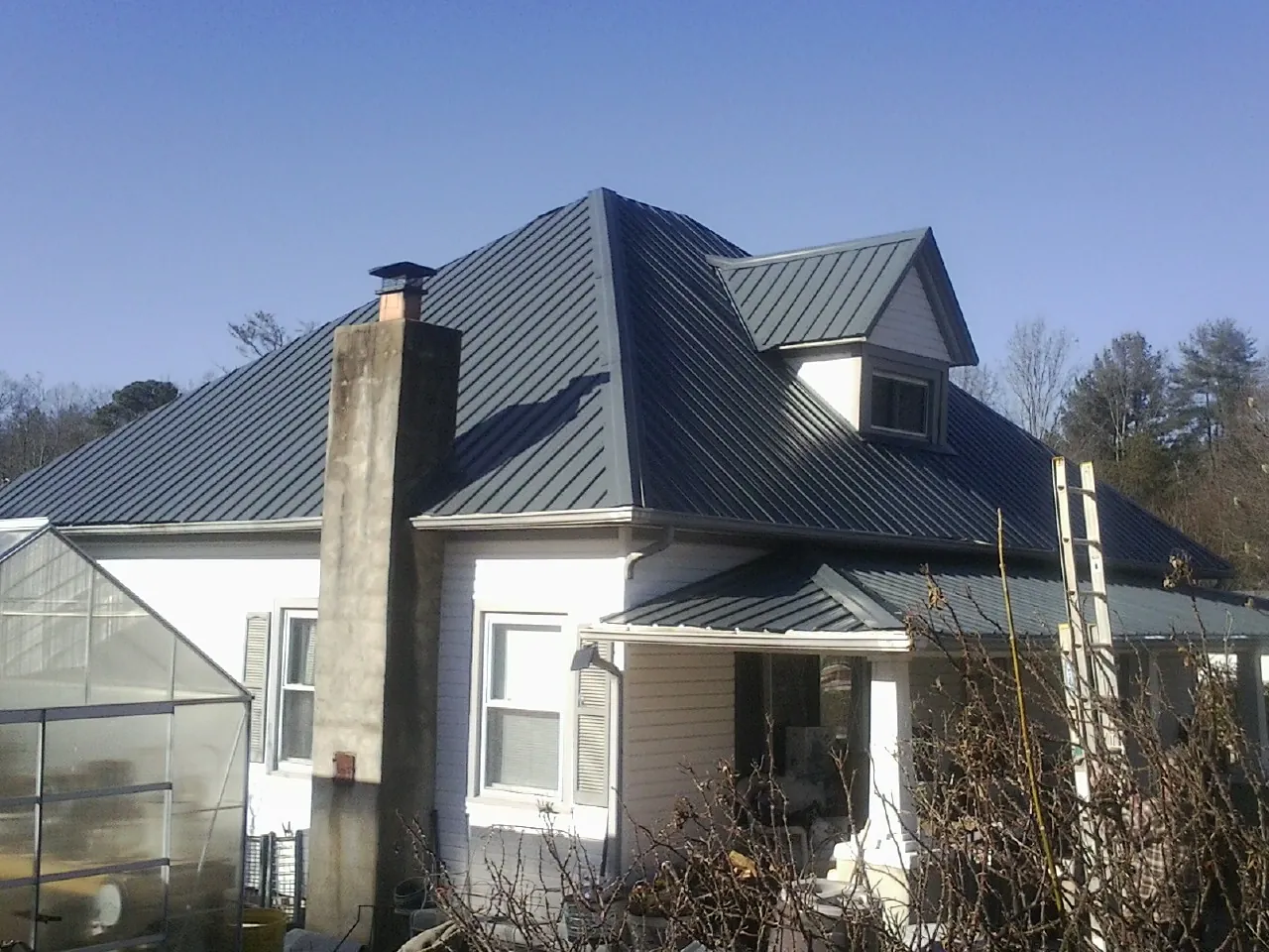 Dark blue standing seam metal roof on a white farmhouse with dormer — Slate & Tile Roof Repair by Roofing Brothers in Mapleton Depot