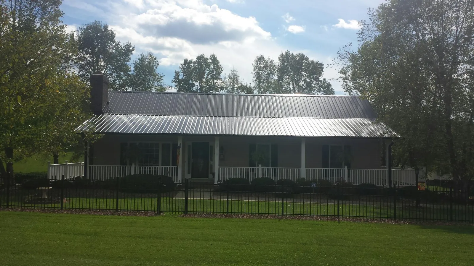 Gray metal roof on a brick ranch with a full width front porch — Gutter Guard Installation work by our crew in Mapleton Depot
