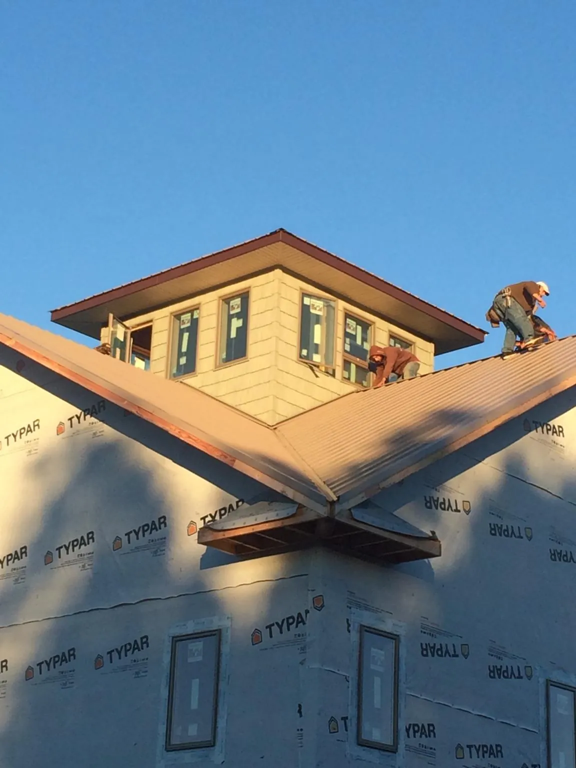 Roofers working around a rooftop cupola on a new metal roof at sunset — Roof Waterproofing in Mapleton Depot by Roofing Brothers